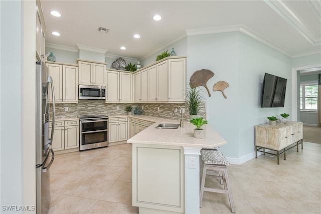 kitchen featuring crown molding, sink, appliances with stainless steel finishes, kitchen peninsula, and a breakfast bar area