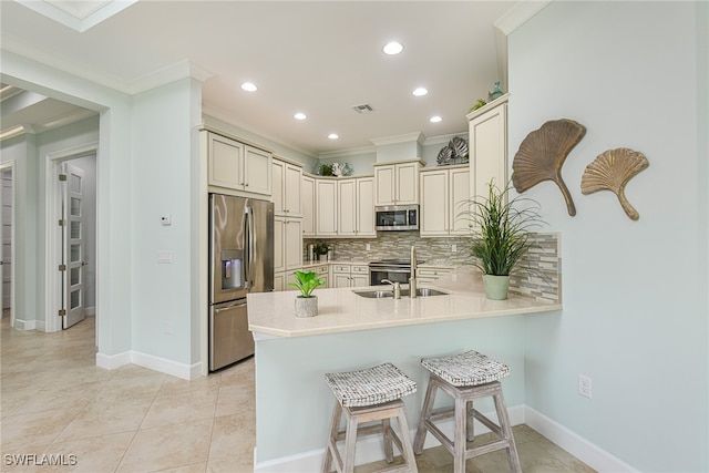 kitchen with decorative backsplash, appliances with stainless steel finishes, crown molding, sink, and cream cabinetry