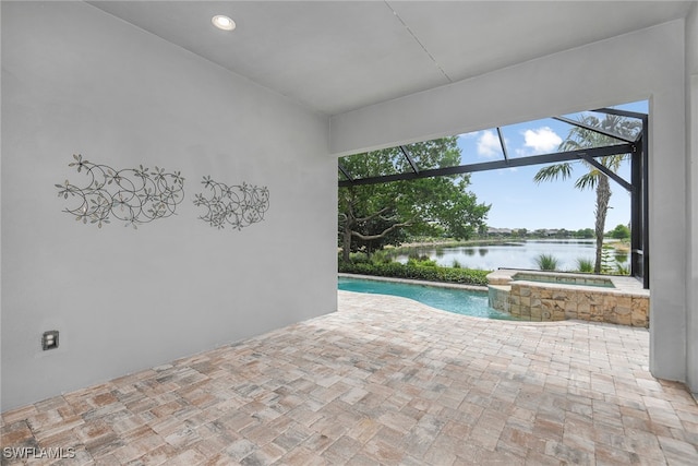 view of pool with glass enclosure, a patio area, a water view, and an in ground hot tub