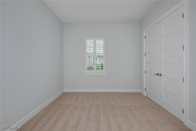 unfurnished bedroom with light carpet and a closet