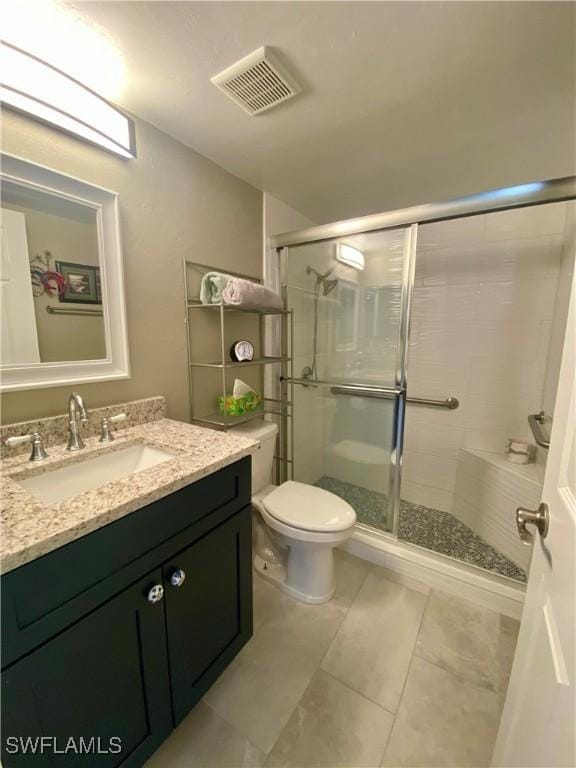 bathroom with vanity, tile patterned flooring, a shower with door, and toilet