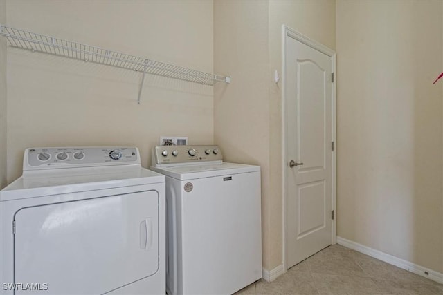 clothes washing area featuring washer and clothes dryer and light tile patterned floors