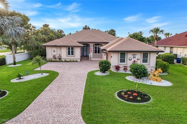 view of front of property featuring decorative driveway, fence, a front lawn, and stucco siding