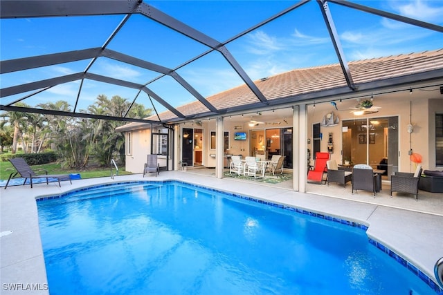 outdoor pool with glass enclosure, ceiling fan, outdoor dining area, and a patio