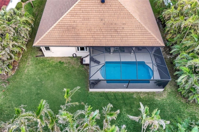 view of swimming pool featuring a yard and glass enclosure