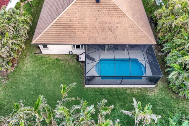 outdoor pool featuring a lanai and a lawn