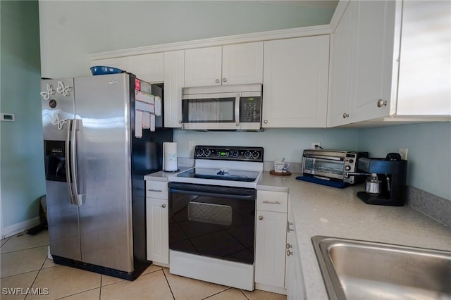 kitchen featuring appliances with stainless steel finishes, light tile patterned floors, white cabinetry, and sink