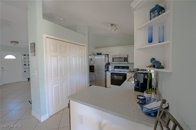 kitchen featuring white cabinetry, kitchen peninsula, lofted ceiling, light tile patterned floors, and appliances with stainless steel finishes