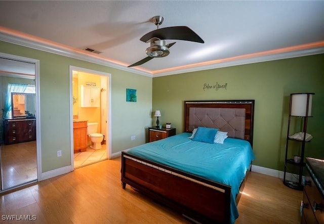 bedroom featuring light wood-type flooring, ensuite bath, ceiling fan, and crown molding