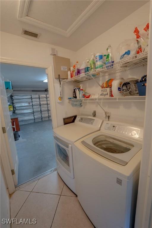 laundry room featuring washer and clothes dryer, ornamental molding, and light tile patterned floors