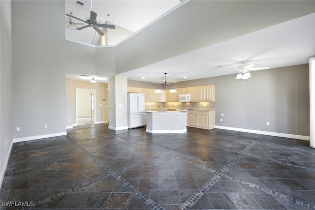 unfurnished living room with a high ceiling and ceiling fan