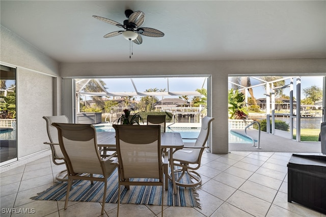 sunroom with ceiling fan, a pool, and a water view