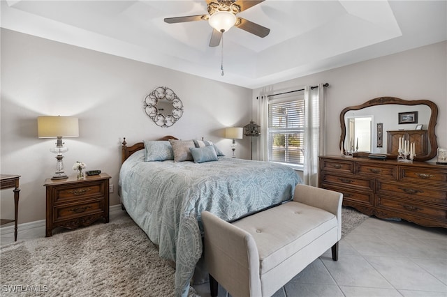 bedroom with light tile patterned floors, ceiling fan, and a tray ceiling