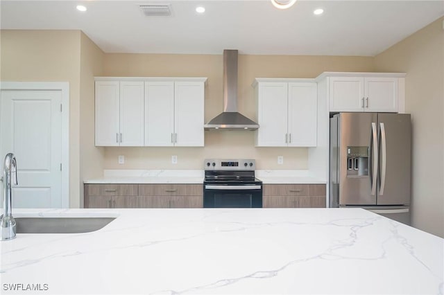 kitchen featuring sink, wall chimney exhaust hood, light stone counters, white cabinetry, and stainless steel appliances