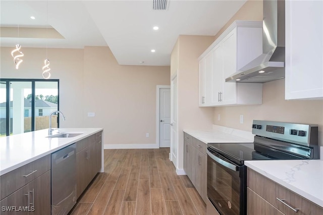 kitchen with wall chimney exhaust hood, sink, white cabinets, and stainless steel appliances