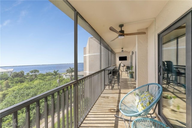 balcony with ceiling fan and a water view