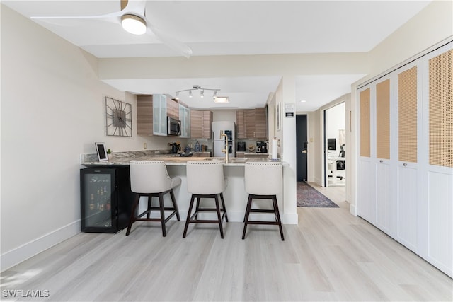 kitchen featuring white fridge, light hardwood / wood-style floors, a kitchen breakfast bar, and kitchen peninsula