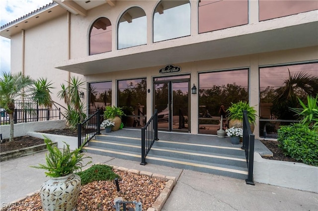 view of exterior entry with fence and stucco siding