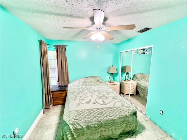 tiled bedroom with ceiling fan, a textured ceiling, and a closet