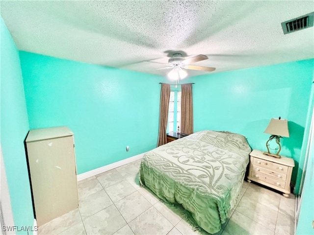 bedroom with ceiling fan, light tile patterned flooring, and a textured ceiling