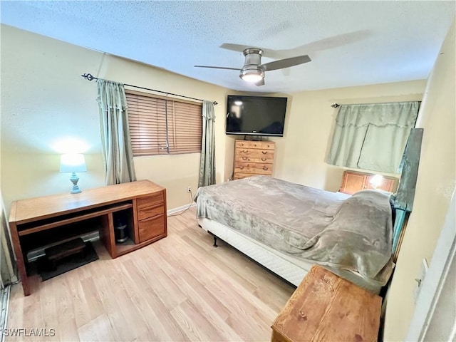 bedroom with ceiling fan, light hardwood / wood-style floors, and a textured ceiling