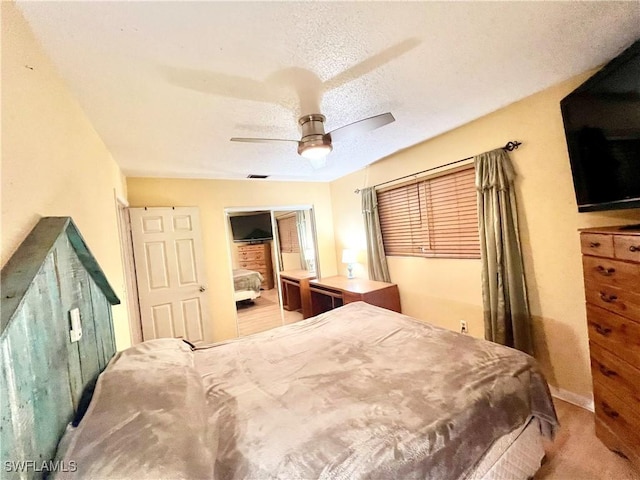 bedroom featuring ceiling fan, light colored carpet, and a textured ceiling