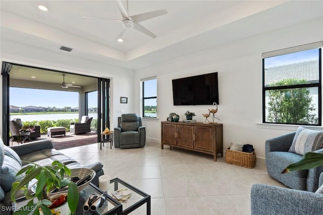 living room with ceiling fan and a water view