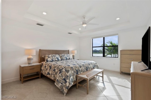 tiled bedroom with ceiling fan and a tray ceiling