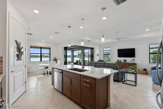 kitchen featuring stainless steel dishwasher, ceiling fan, sink, a center island with sink, and hanging light fixtures