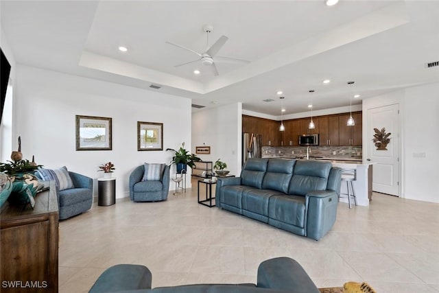 tiled living room featuring ceiling fan and a raised ceiling