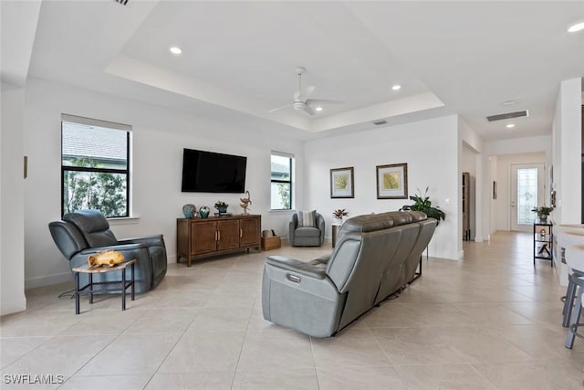 living room with ceiling fan, light tile patterned flooring, and a tray ceiling