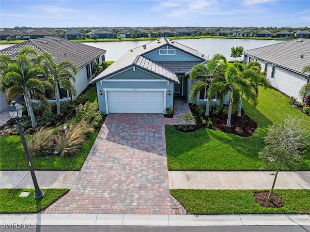 view of front facade with a front yard, a garage, and a water view