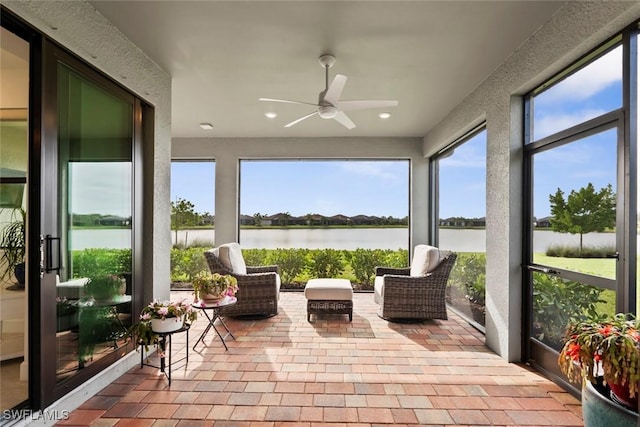 sunroom / solarium featuring ceiling fan and a water view