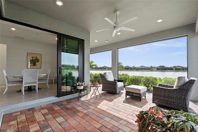 sunroom / solarium with ceiling fan and a water view