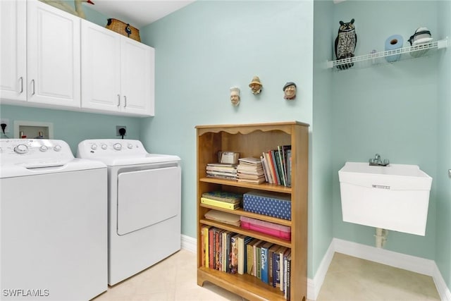 washroom featuring separate washer and dryer, light tile patterned floors, sink, and cabinets