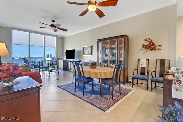 tiled dining room with ornamental molding, expansive windows, ceiling fan, and a water view