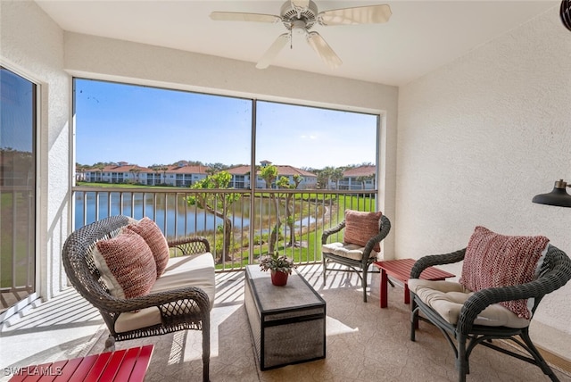 sunroom with a ceiling fan and a water view