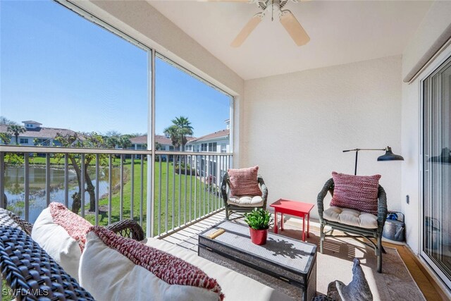 sunroom / solarium featuring a water view and ceiling fan