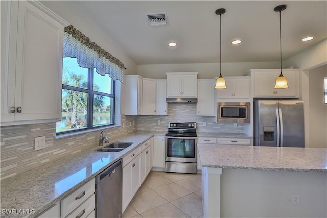 kitchen with light stone counters, stainless steel appliances, sink, pendant lighting, and white cabinetry