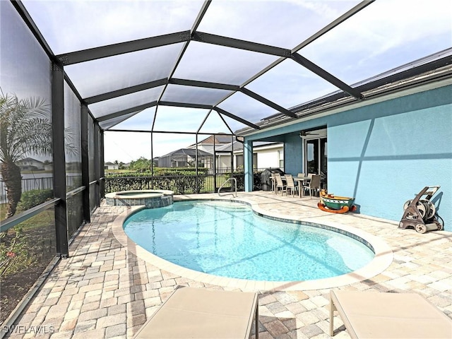 view of pool featuring glass enclosure, a patio area, and an in ground hot tub