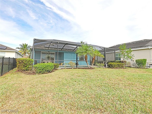 rear view of house featuring a yard and glass enclosure