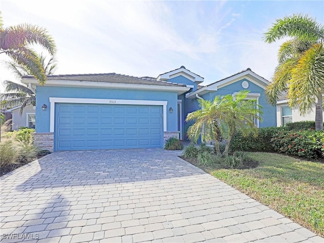 view of front of property featuring stone siding, stucco siding, a garage, and decorative driveway