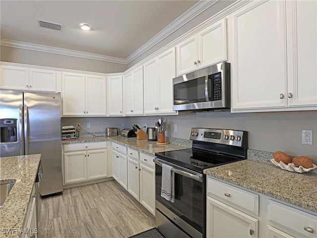 kitchen featuring white cabinets, stainless steel appliances, light stone countertops, and crown molding