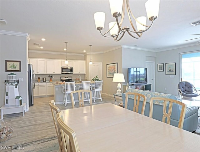 dining room with a notable chandelier, light hardwood / wood-style floors, and ornamental molding