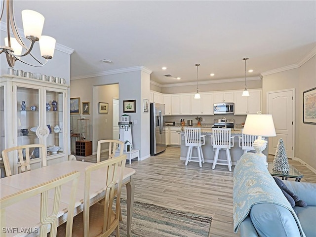 dining room featuring light wood-type flooring, crown molding, and an inviting chandelier