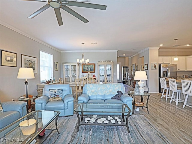 living room featuring ceiling fan with notable chandelier, wood-type flooring, and crown molding