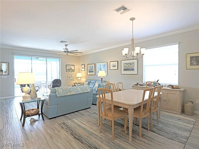 dining room with ceiling fan with notable chandelier, light hardwood / wood-style flooring, and crown molding