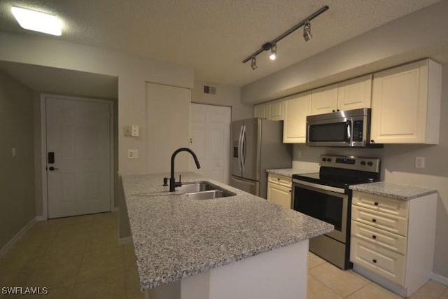 kitchen featuring stainless steel appliances, white cabinets, a textured ceiling, and light stone countertops