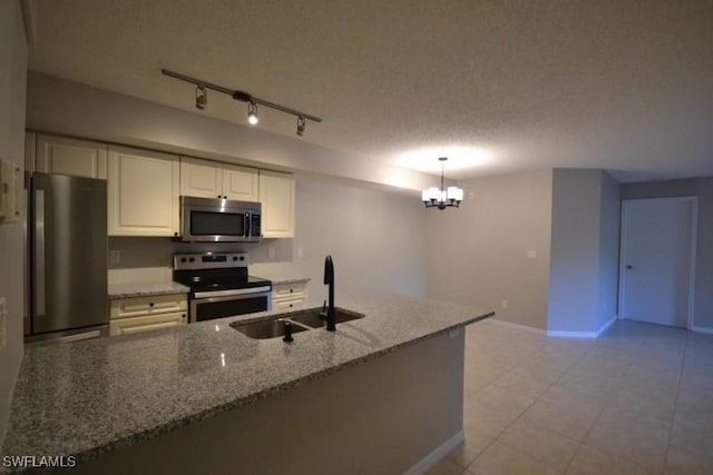 kitchen featuring a textured ceiling, hanging light fixtures, light stone countertops, a chandelier, and appliances with stainless steel finishes