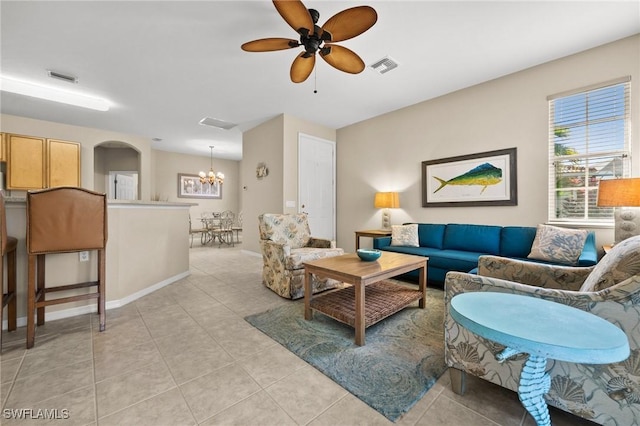 tiled living room featuring ceiling fan with notable chandelier